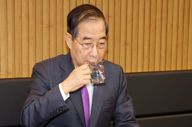 한덕수 대통령 권한대행 국무총리가 16일 결식 아동들에게 무료 점심을 제공해온 울산 뚠뚠이 돈가스에서 사장과 직원들을 격려한 후 물을 마시고 있다. 연합뉴스.